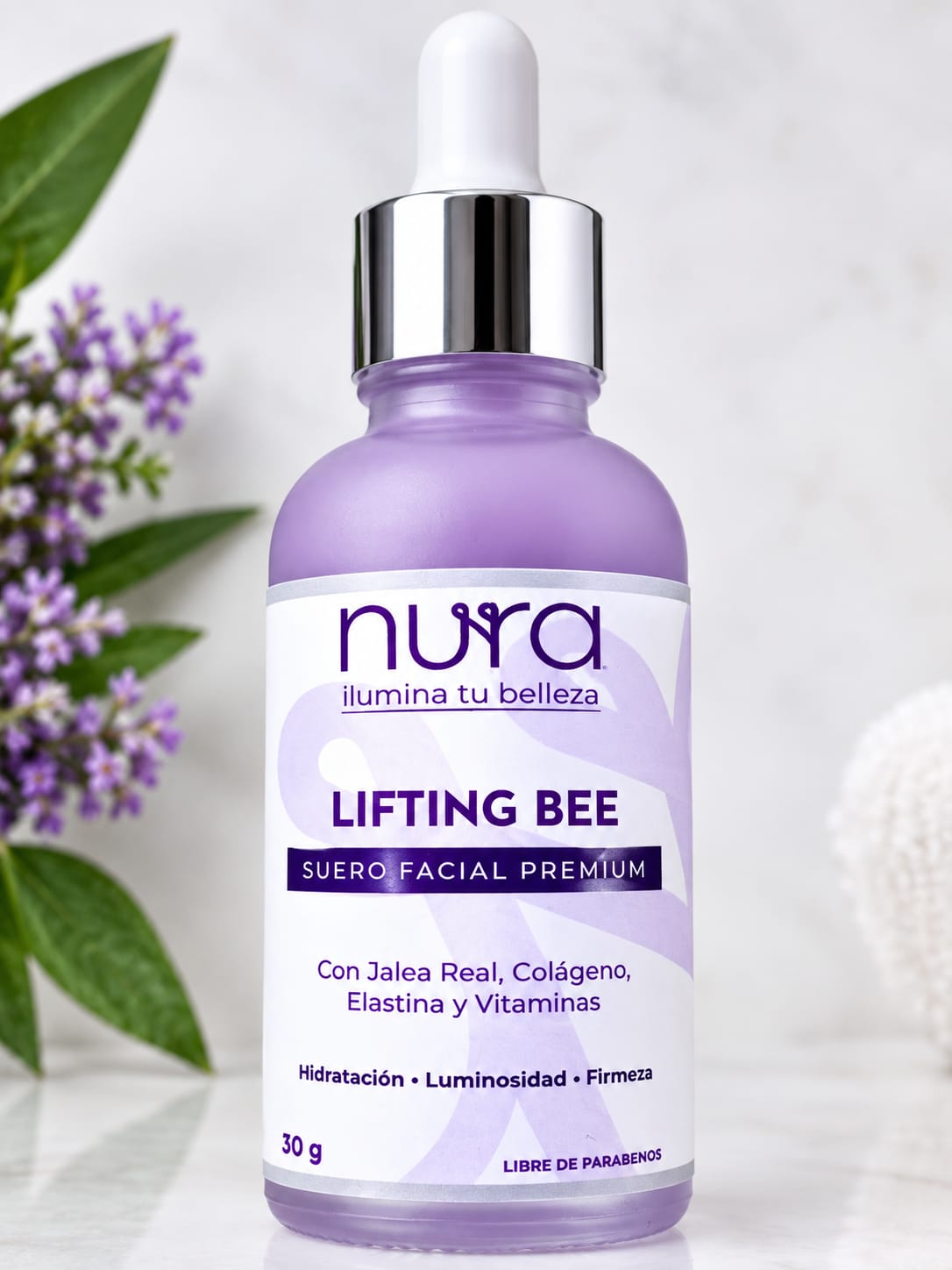 Frasco con gotero de Lifting Bee de NURA, suero facial premium, junto a flores de lavanda